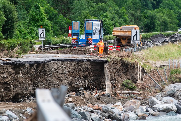 La chaussée de l'A13 a rompu sous l'effet des eaux déchaînées de la Moesa. Les travaux de comblement ont commencé. © KEYSTONE/SAMUEL GOLAY